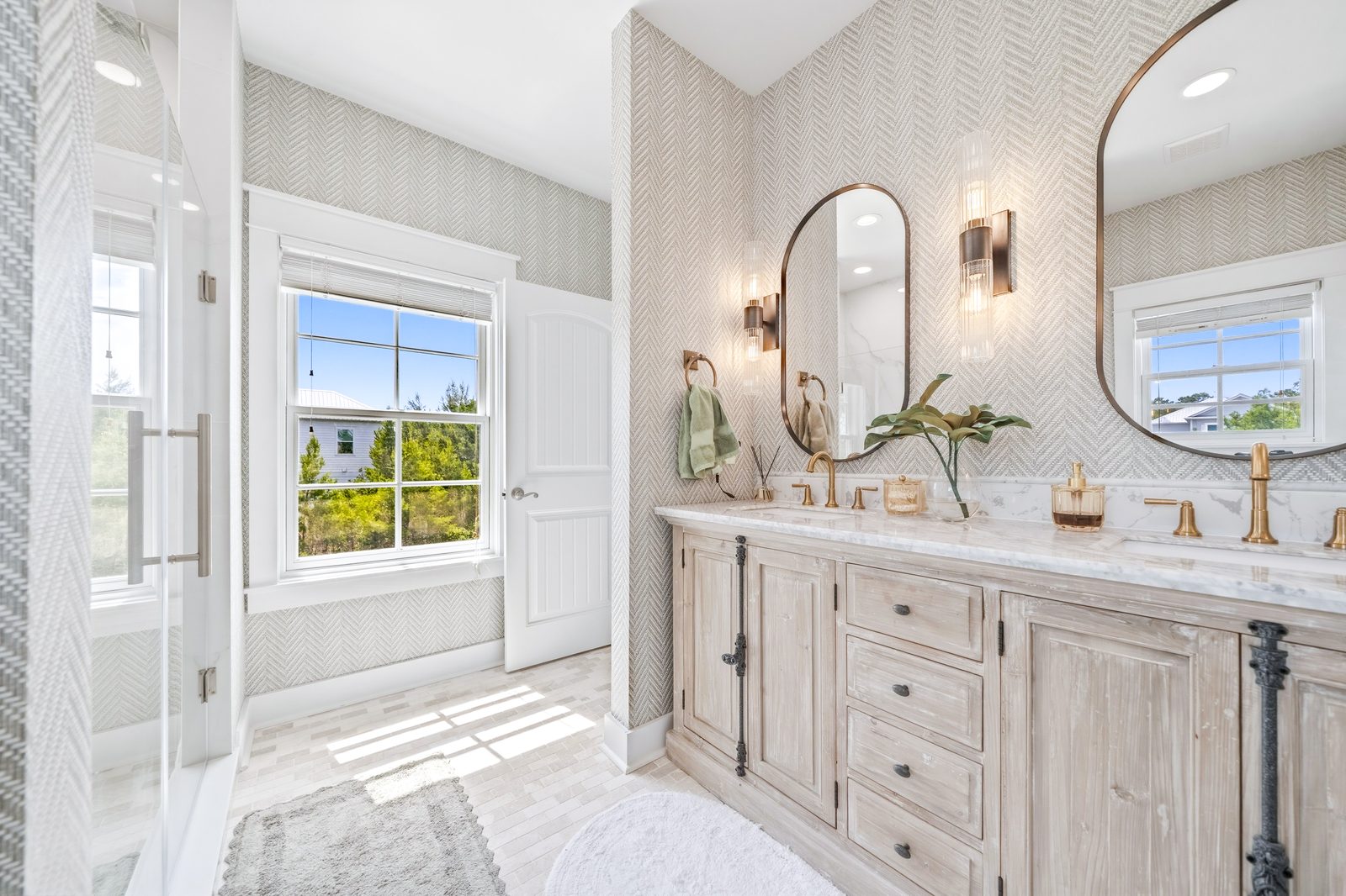 Primary bathroom with herringbone wallpaper and double vanity